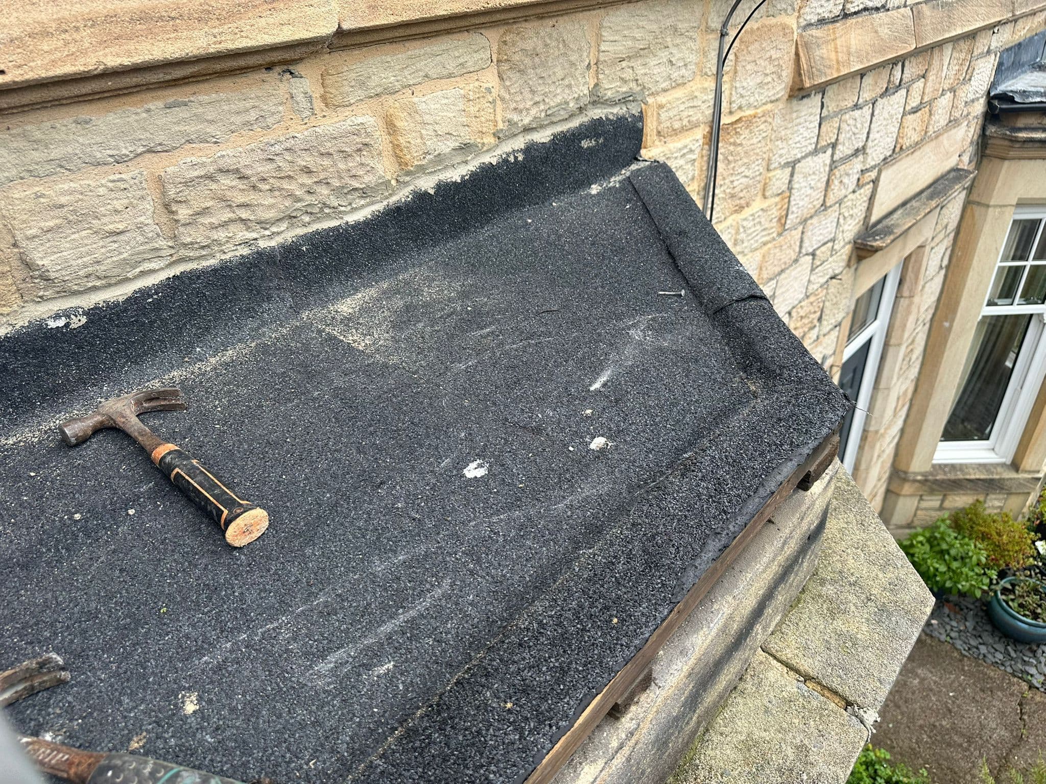 Felt flat roof being repaired on a stone property